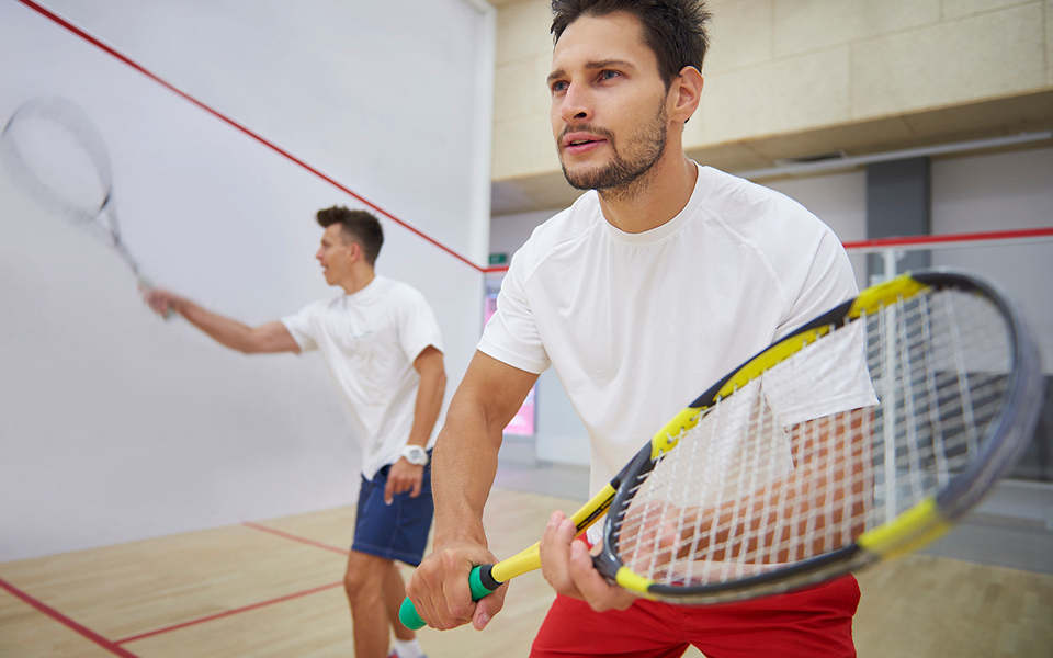 Two men playing squash on indoor court.