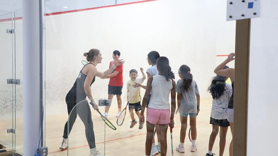 Children and adults playing squash on court.