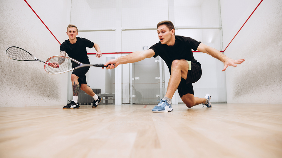 Two men playing squash in court.