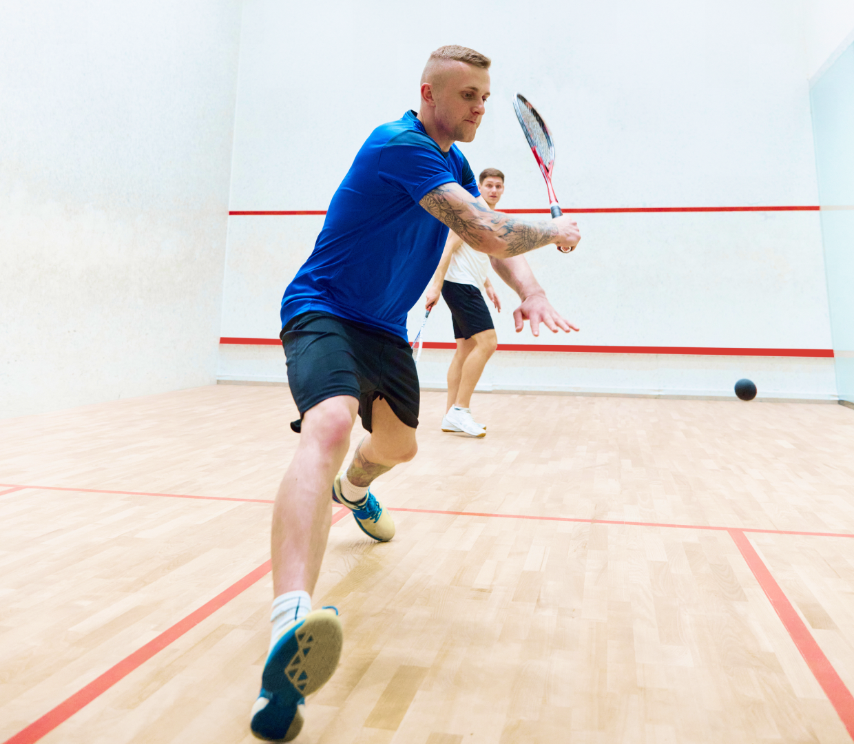Two men playing squash on indoor court.