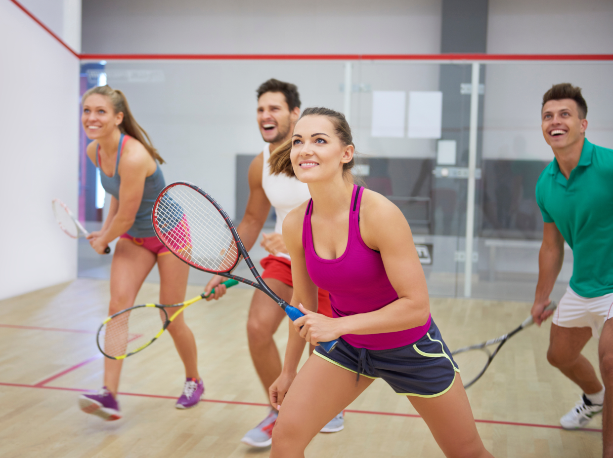 Group playing squash on indoor court.